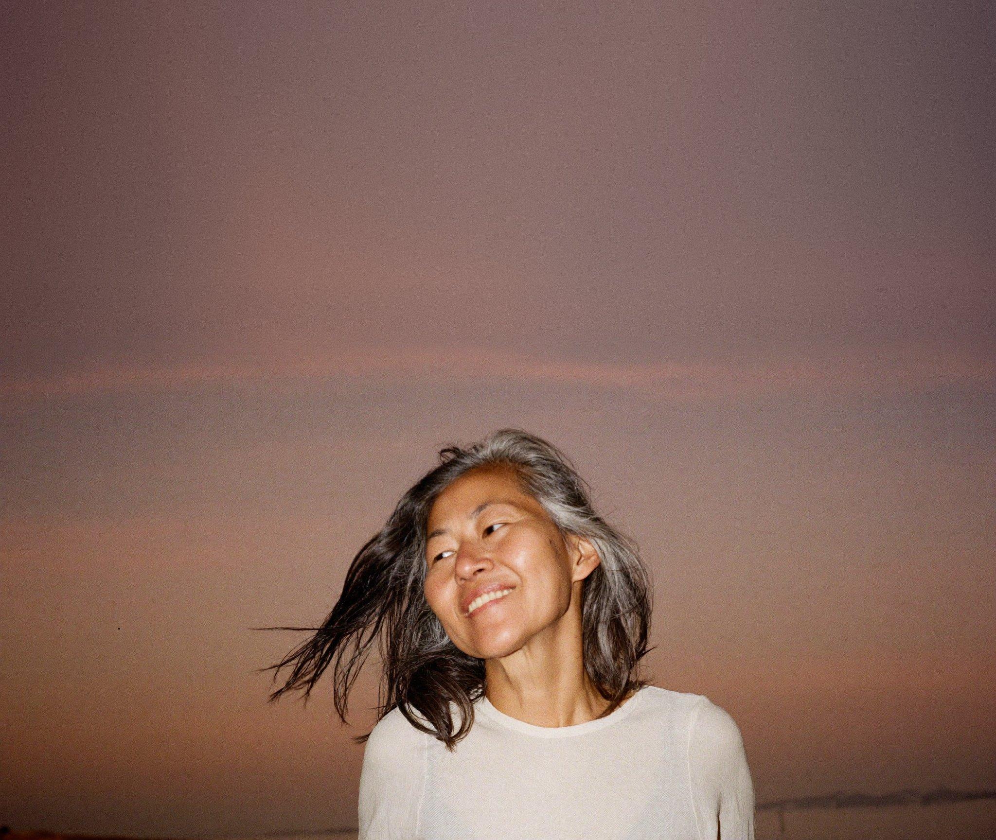 A woman in her fifties by Manila Bay at dusk, smiling