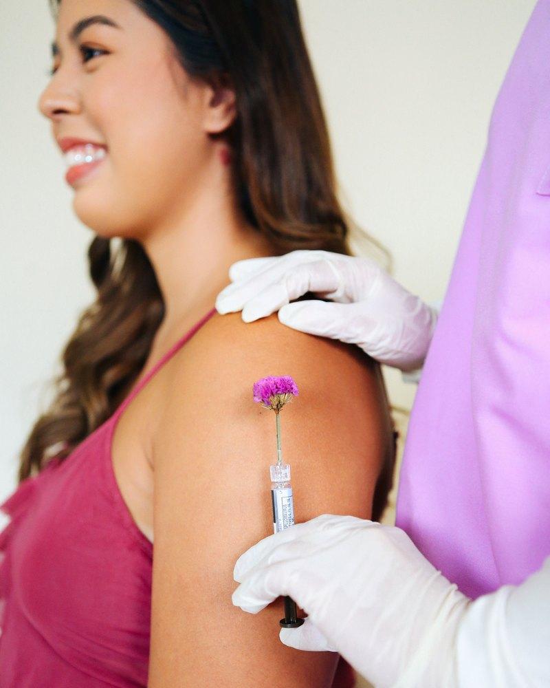 A Kindred patient smiling as a clinician gives her the vaccine in her upper arm